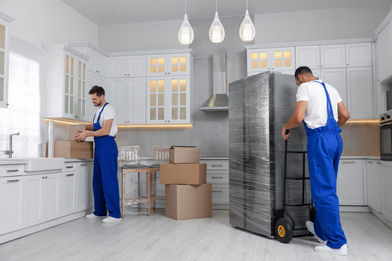 Movers unpacking boxes in modern kitchen.