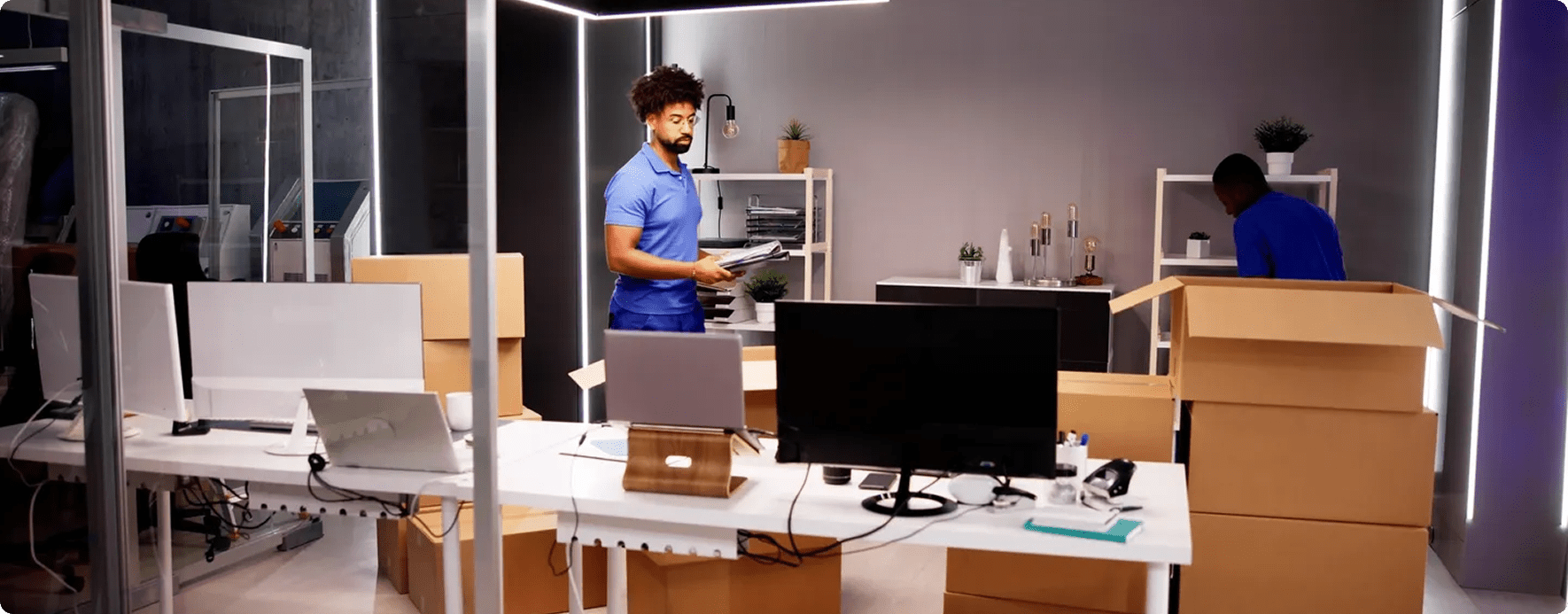 Office workers packing boxes in modern workspace.