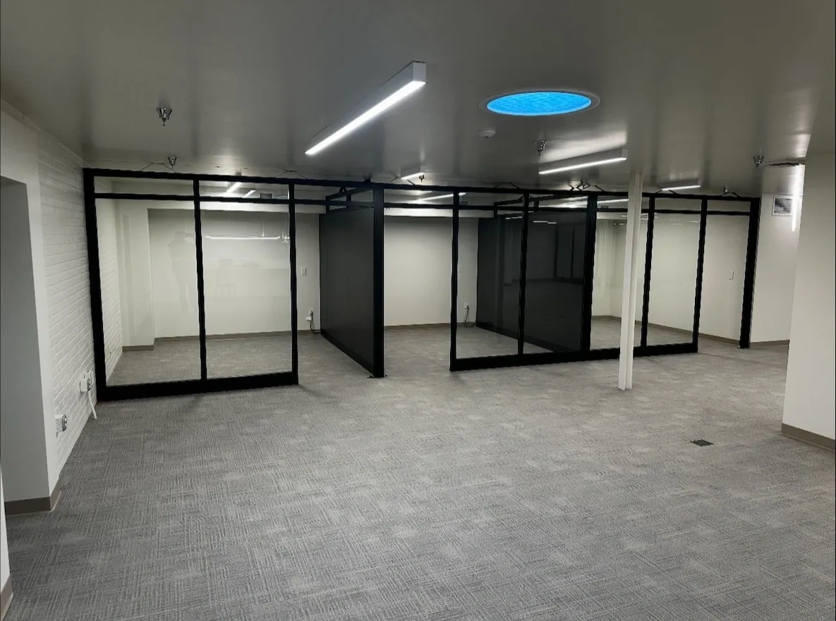 Empty room with glass partitions and tiled floor under ceiling lights.